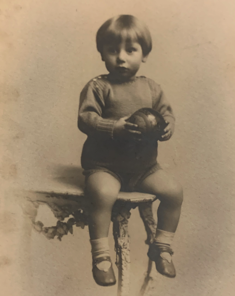 Alec Frank MacKelden as a young child, seated on a bench holding a ball, c. mid-1920s